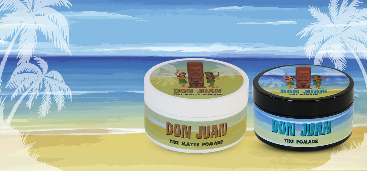 Two jars of Don Juan Tiki Matte Pomade on a beach background with palm trees and blue sky.